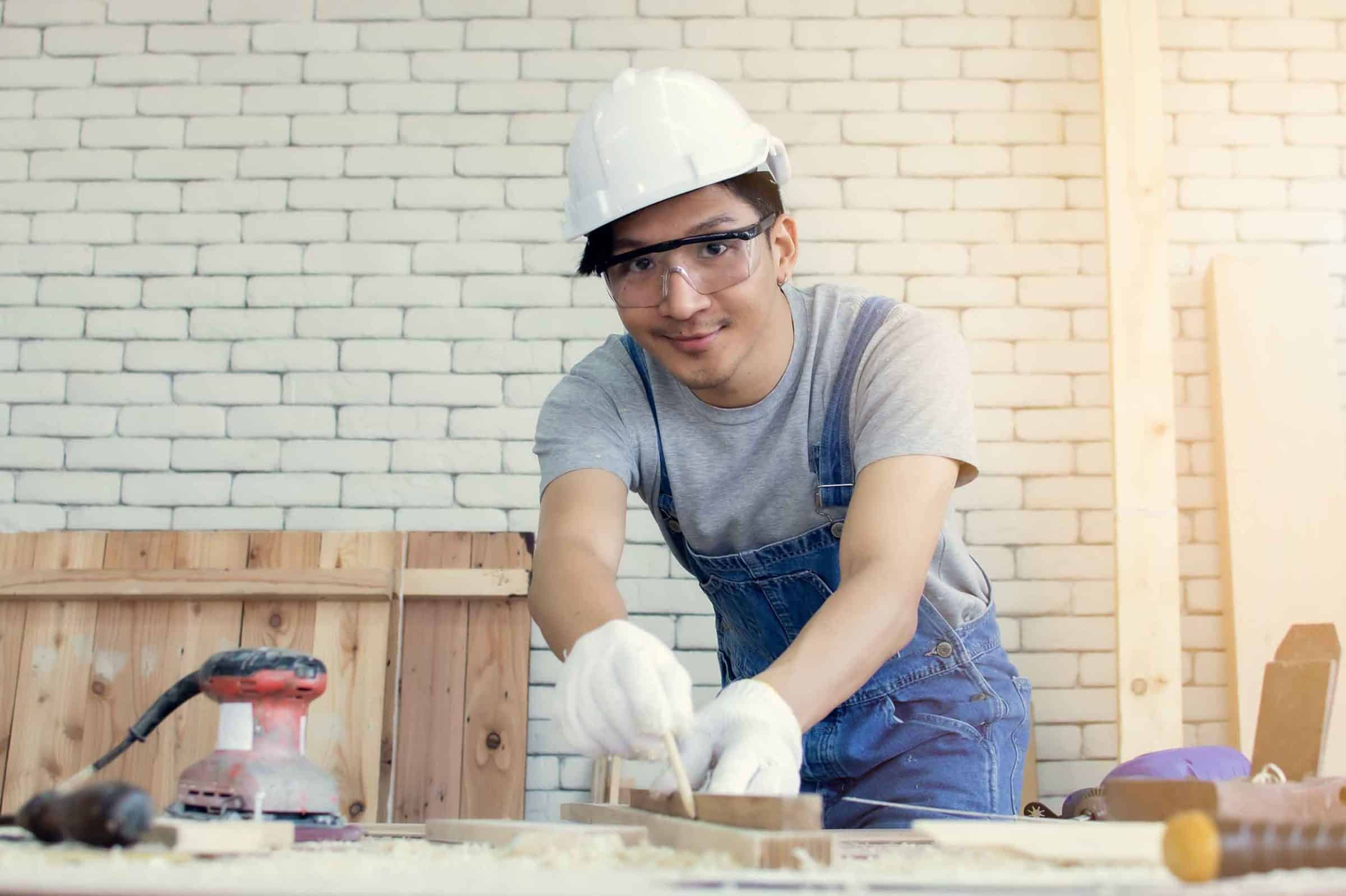 Construction worker smiling while sanding wood